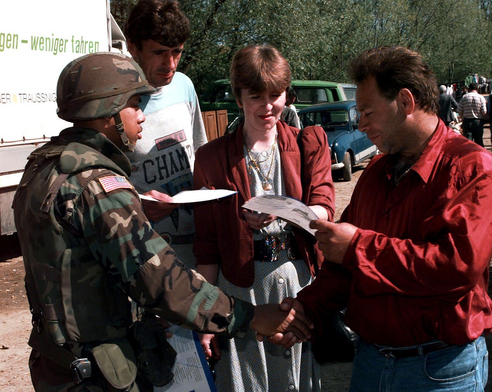 U.S. Army Sgt. Warren Lewis greets local Muslim shoppers in Tojsici.