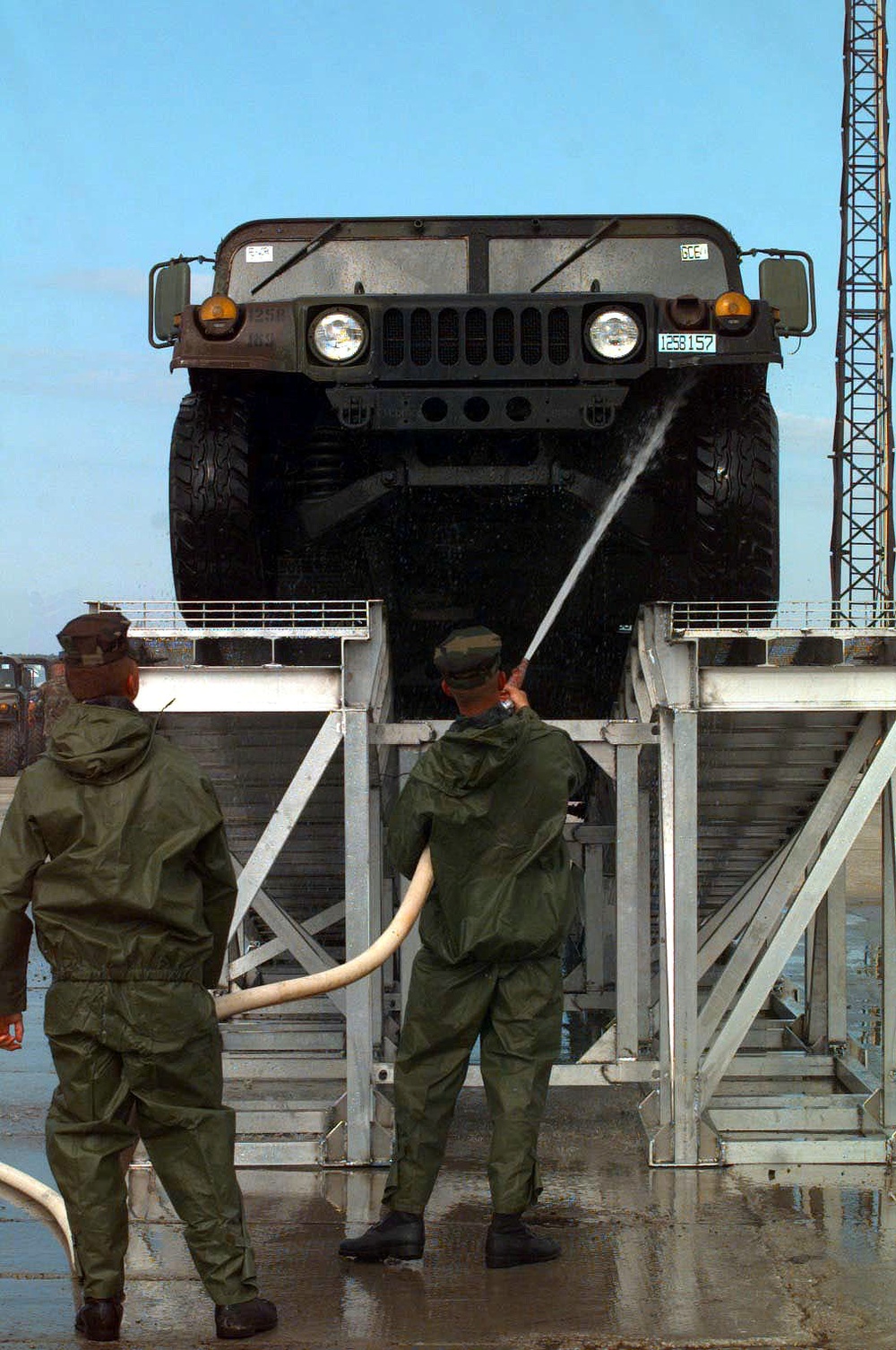 Two Marines wash the underside of a Humvee at the port facility in Paldiski, Estonia.