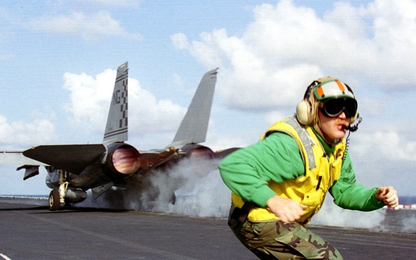 Petty Officer Macaby moves to ready the next aircraft for launch from the USS Nimitz.