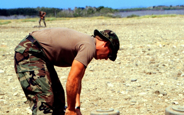 Petty Officer 1st Class Ullel excavates an area to stack land mines for destruction.