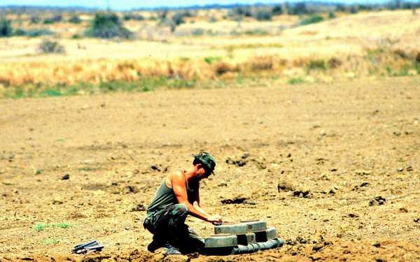 EOD technician places an explosive into a stack of deactivated land mines.