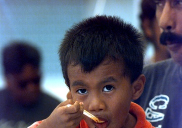 A little boy has a Humanitarian Meal Ready to Eat at Andersen Air Force Base, Guam.