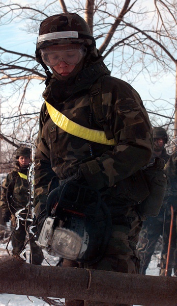 A soldier from the 642nd Engineer Company uses a chain saw to clear fallen trees.