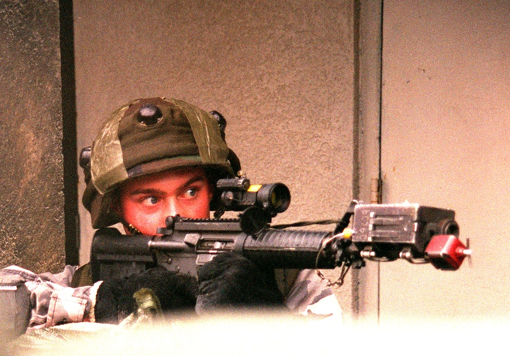 A Marine looks down the scope of his M-16A2 rifle in the MOUT facility.