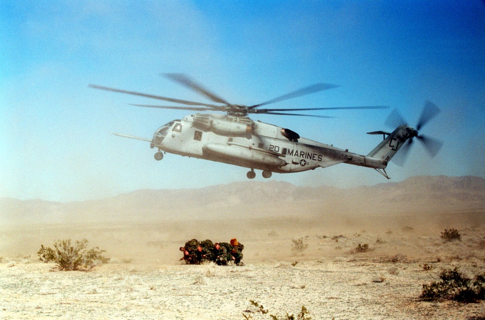 A reconnaissance team braces against the blast of rotor wash from a CH-53E Sea Stallion.