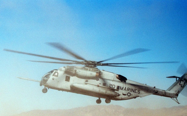 A reconnaissance team braces against the blast of rotor wash from a CH-53E Sea Stallion.