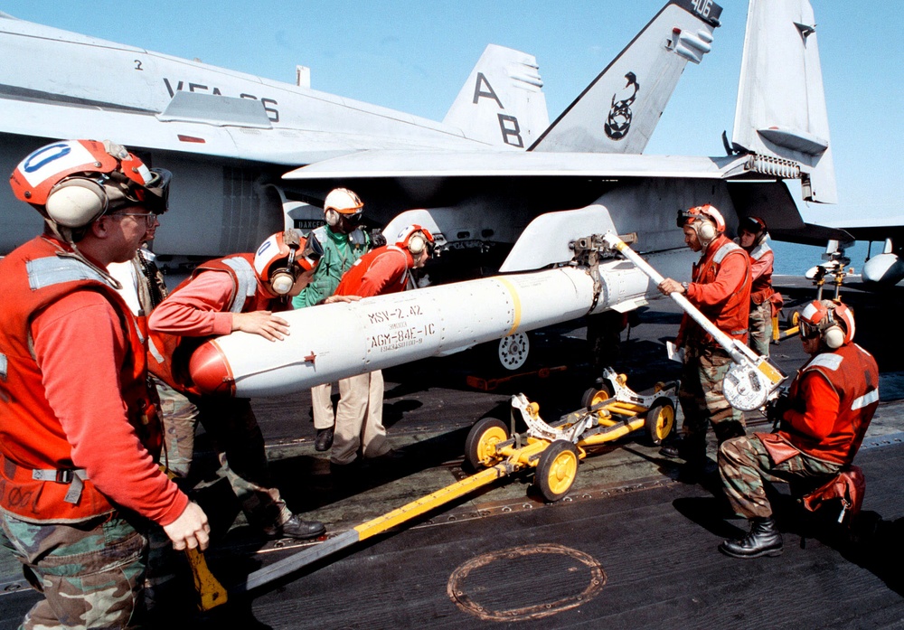 Aviation ordnancemen load an AGM-84E Standoff Land-Attack Missile onto an F/A-18C Hornet.