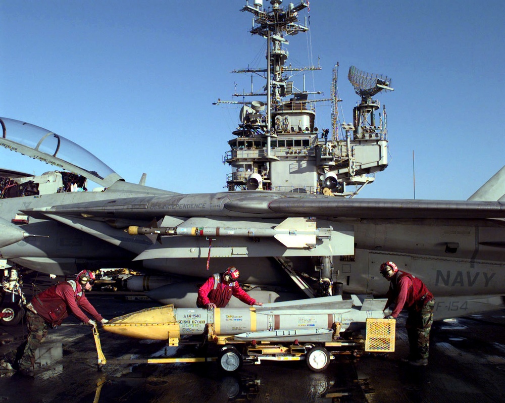 Sailors prepare to load an AIM-54C Phoenix missile onto the wing of an F-14 Tomcat.