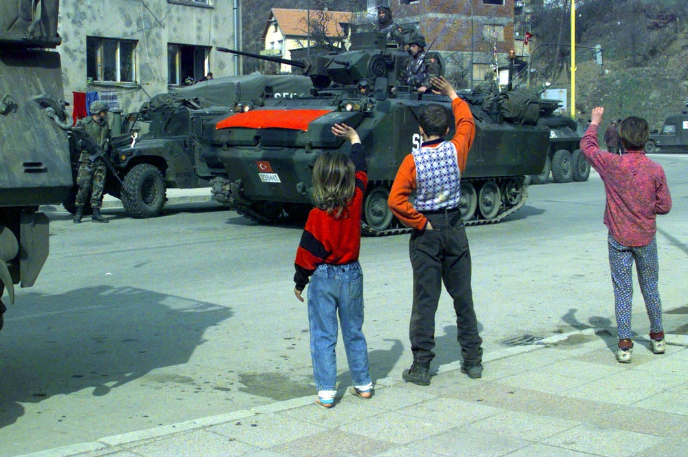 Children wave to a column of Turkish tanks outside Vitkovici, Bosnia and Herzegovina.