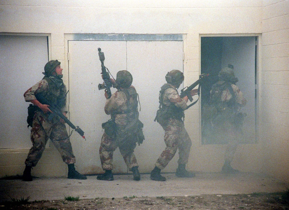 Marines are nearly obscured by smoke as they maneuver through the MOUT facility.