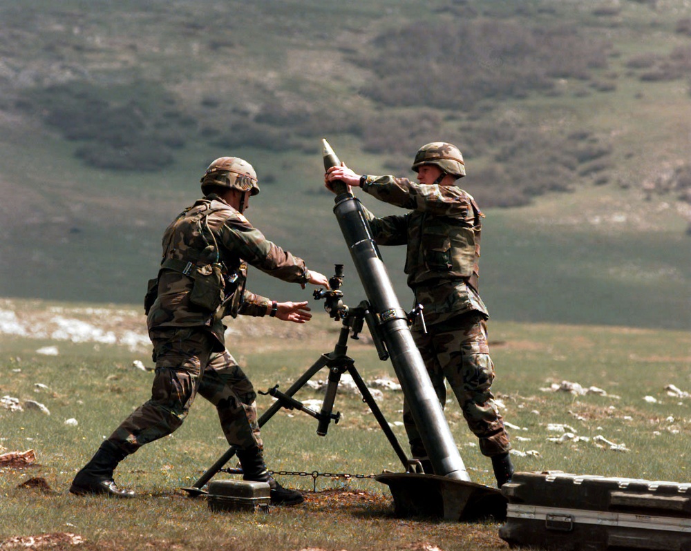 Two U.S. Army soldiers launch a mortar round on the live fire range at Glamoc.