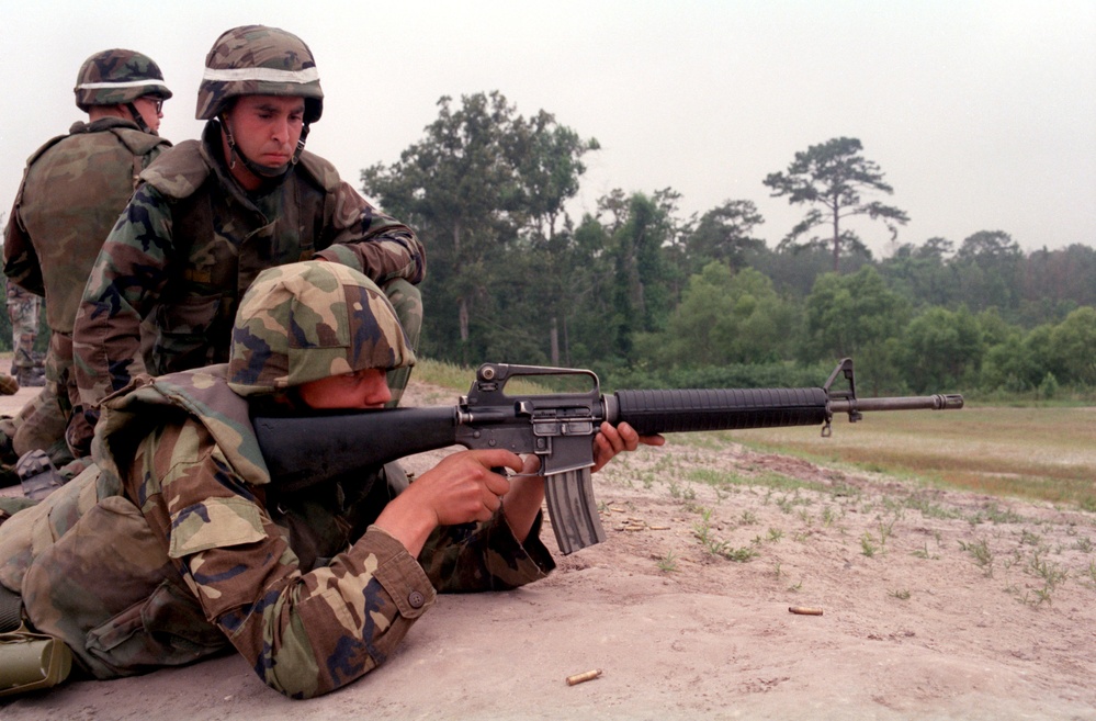 U.S. Marine Cpl. Mark instructs a Latvian soldier on firing an M-16A2 service rifle.