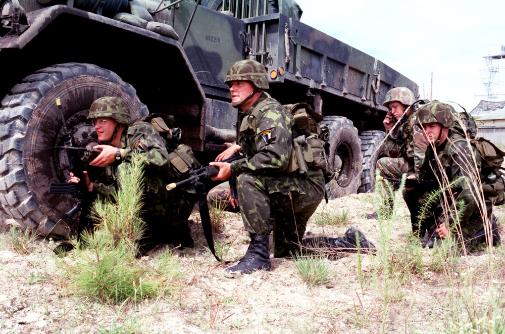 Estonian soldiers crouch alongside an M923 5 ton truck as they wait for further orders.