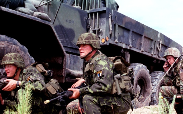 Estonian soldiers crouch alongside an M923 5 ton truck as they wait for further orders.
