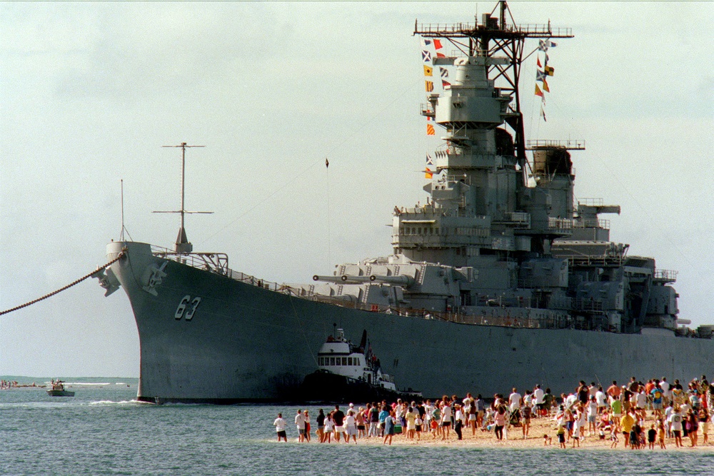 People gather on the beach to see the USS Missouri (BB 63) enter the channel into Pearl Harbor.