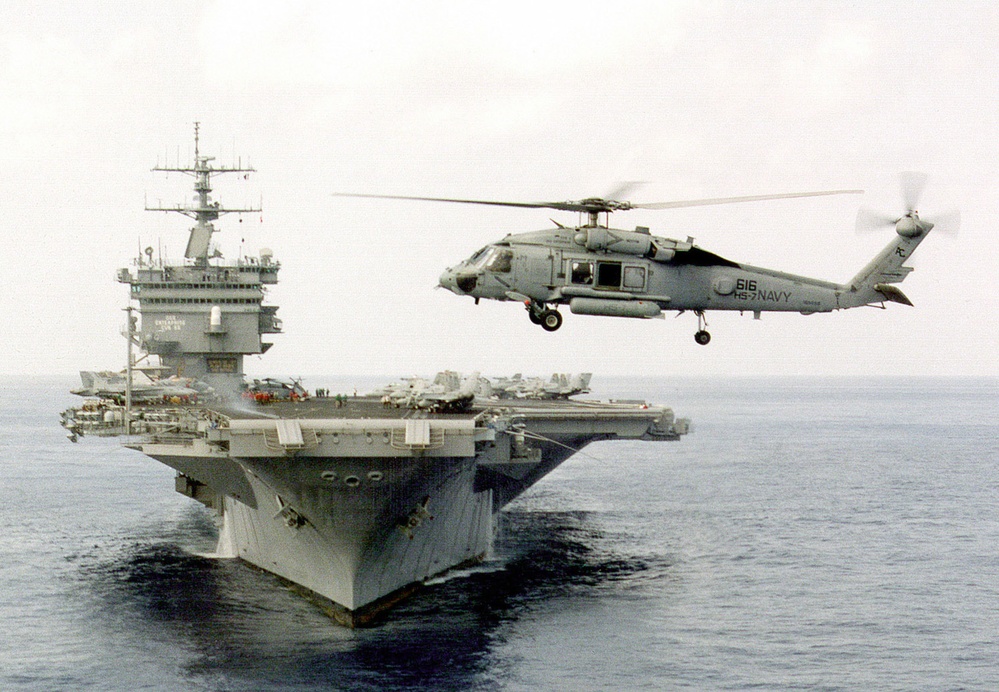 An SH-60 helicopter hovers off the bow of USS Enterprise CVN 65.