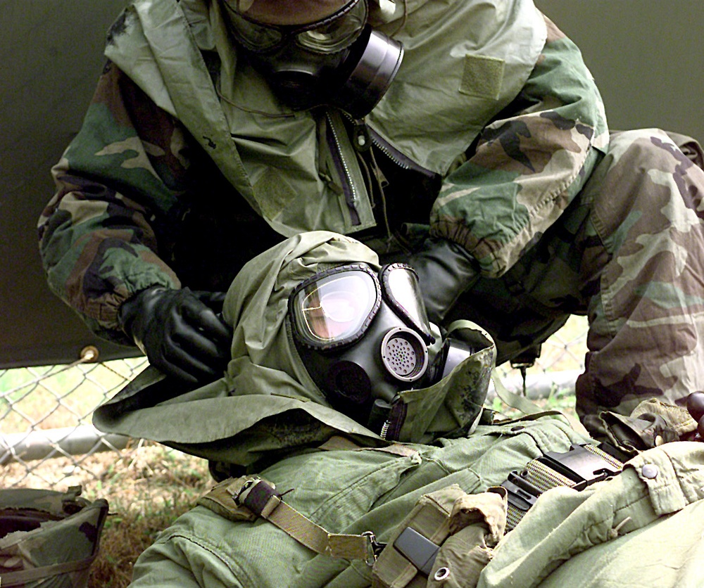 Pvt. Mateo-Gomez (above) adjusts Pfc. Bower's (below) gas mask after a simulated nerve agent attack.