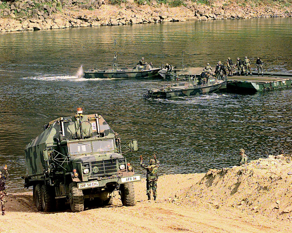 A U.S. Army M-945 Bridge Transporter is guided down to the  edge of the Imjin River.
