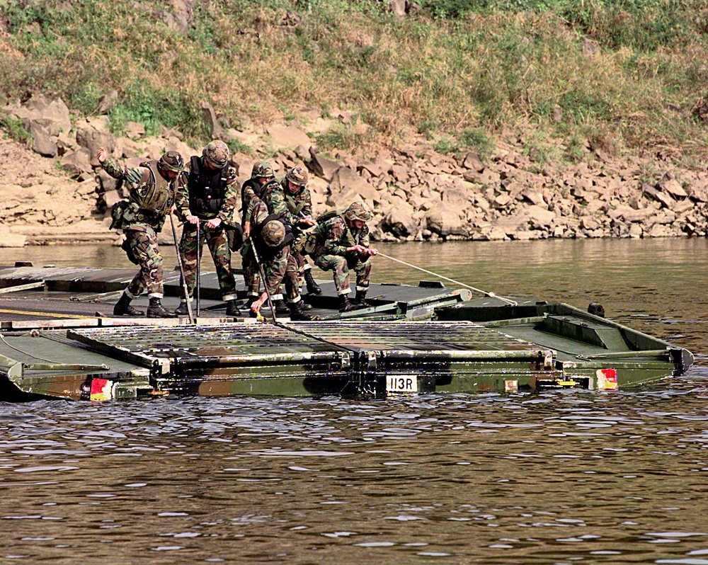 Soldiers use muscle to pull together two sections of pontoon bridge on the Imjin River.