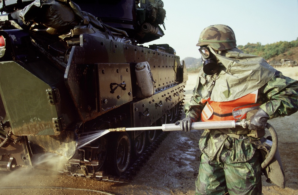 Spc. Shewfelt uses a pressure washing system to decontaminate an M-3 Bradley.
