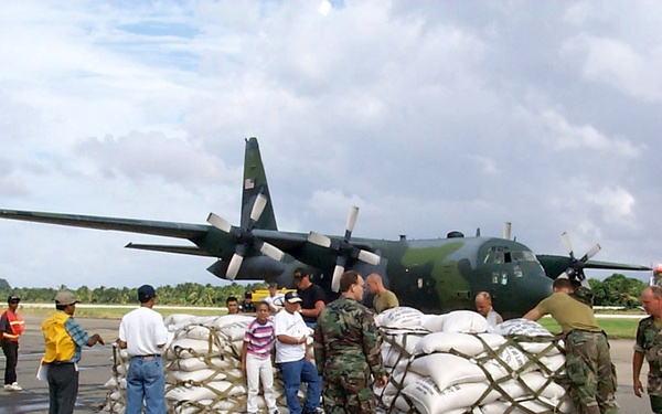 Hondurans, U.S. service men, and Netherlands service men prepare pallets of rice sacks.