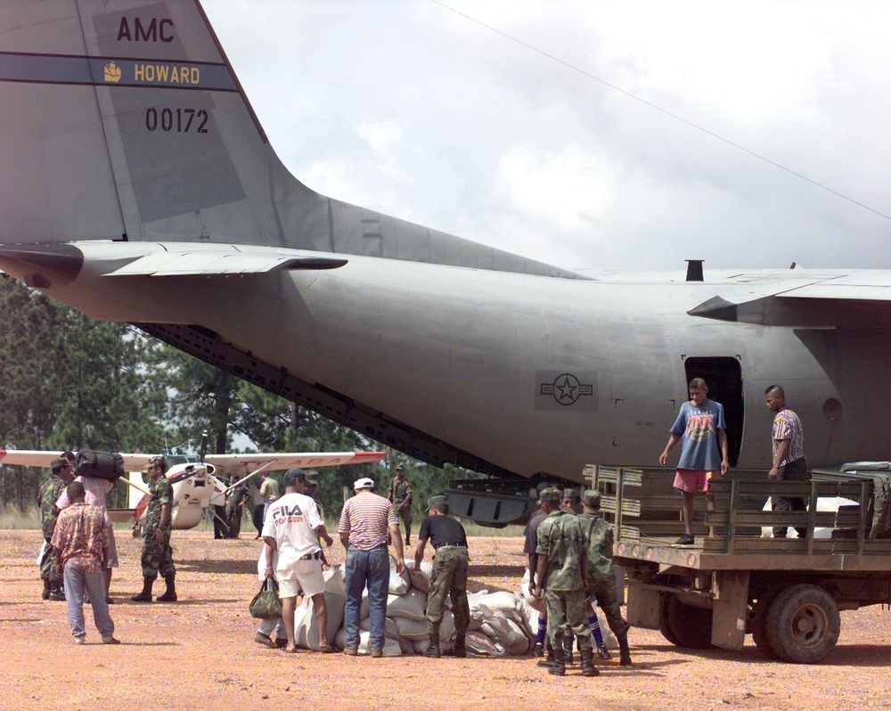 Members of the Honduran military and civilian volunteers help sort a pile of disaster relief supplies.