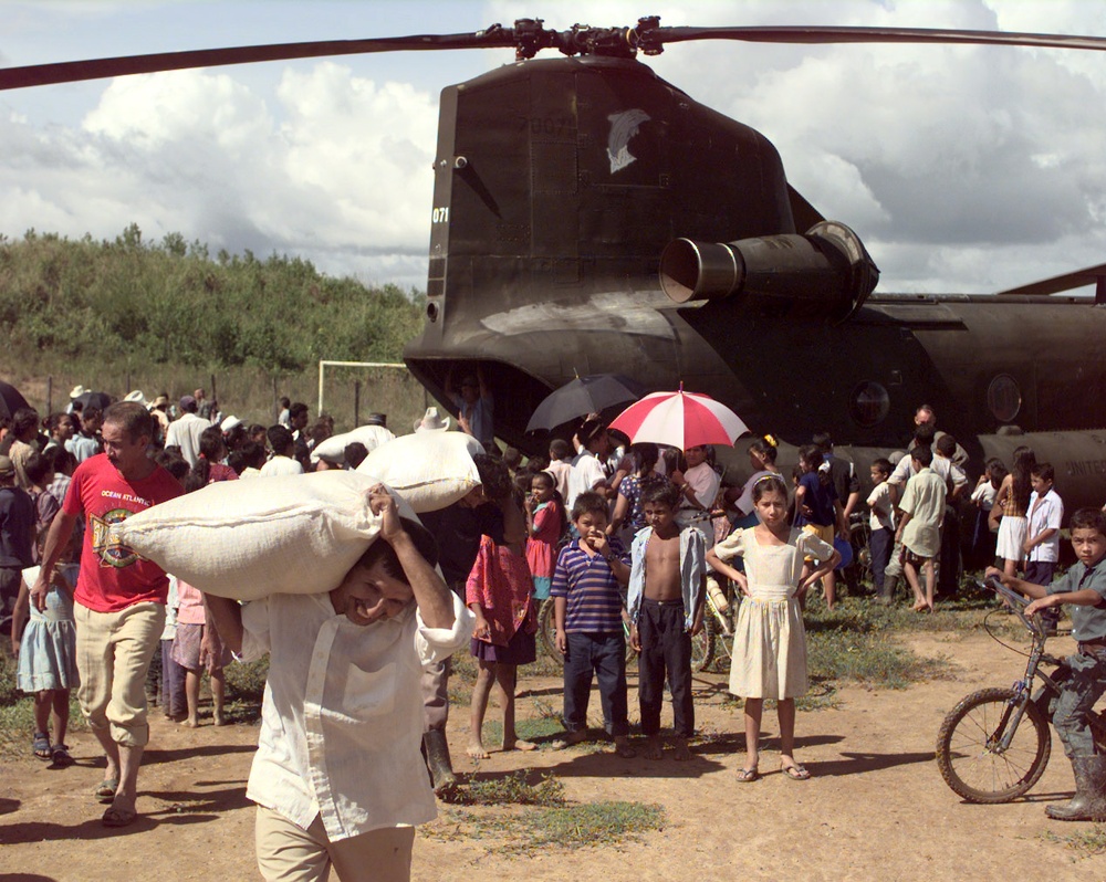A man in Casamacoa, Honduras, carries a sack of corn away from a U.S. Army CH-47 Chinook.