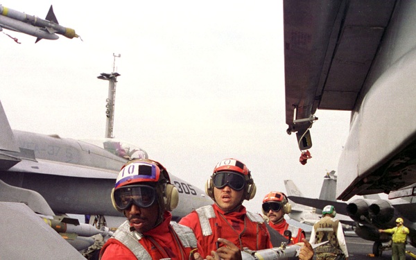 Aviation ordnancemen use teamwork and brute strength to load an AIM-9M Sidewinder.