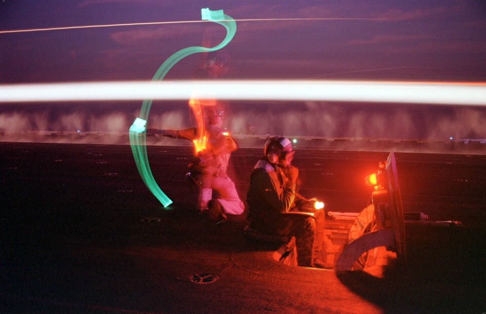 Night time flight operations on the flight deck of the USS Enterprise become a ballet of light.