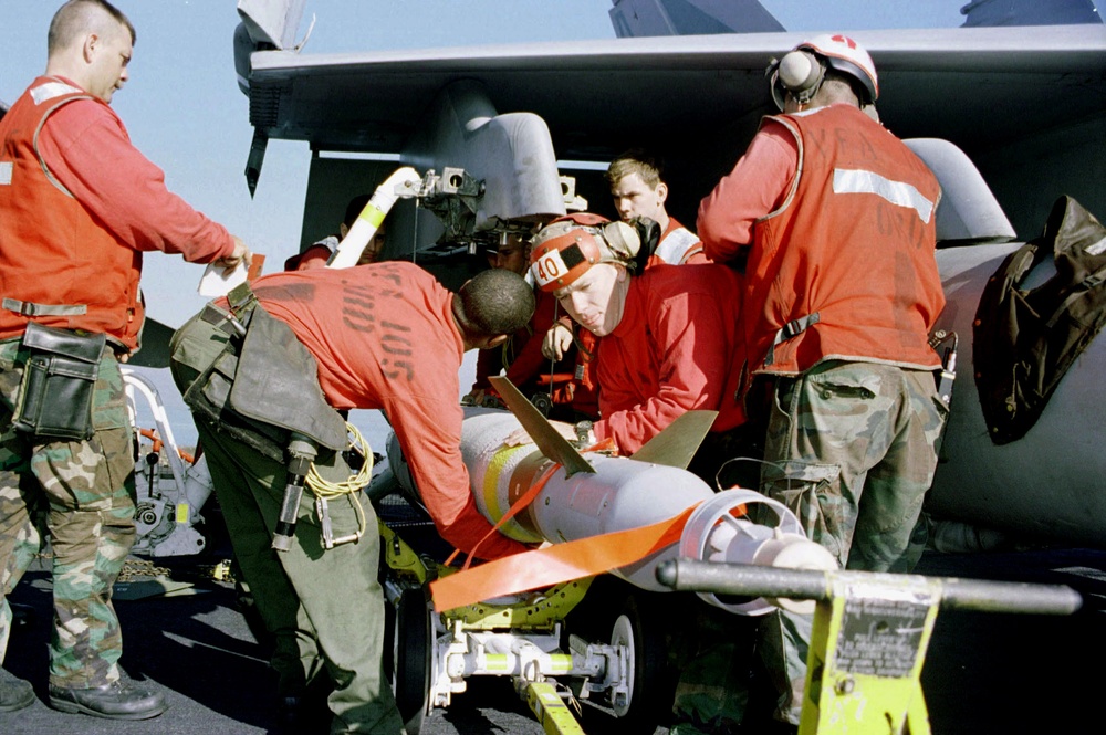 Aviation ordnancemen load an F/A-18 Hornet with a GBU-16 laser guided bomb.