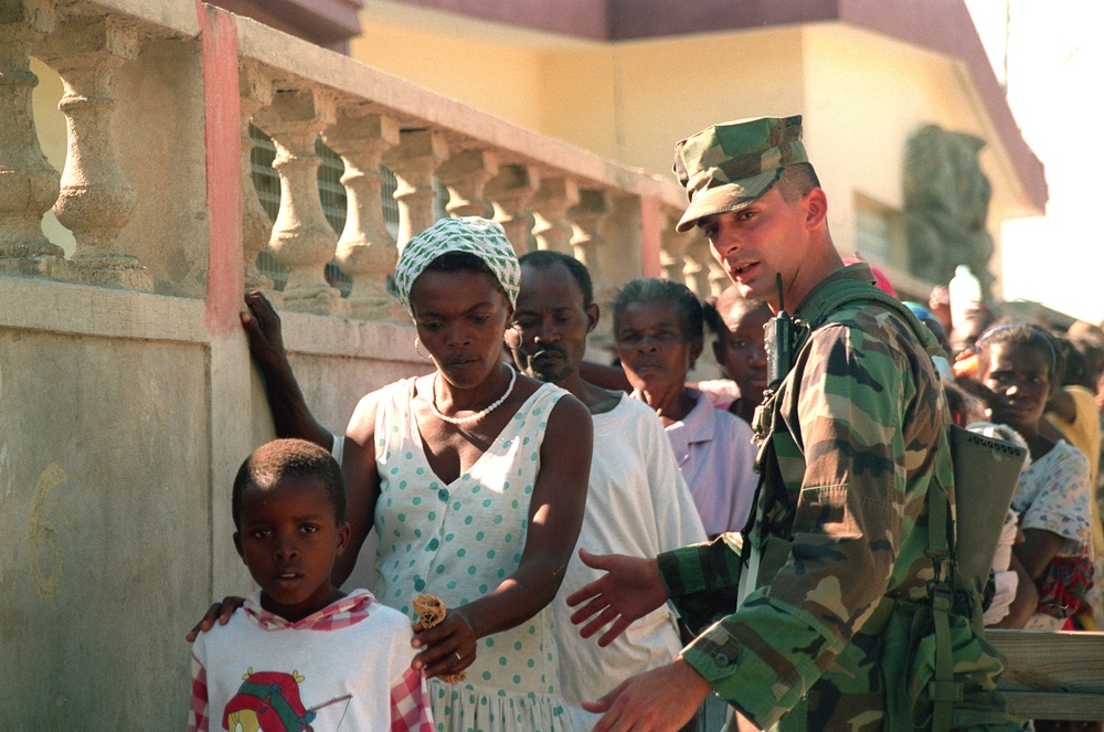 Cpl. Walsh allows a Haitian mother and son through a security checkpoint.
