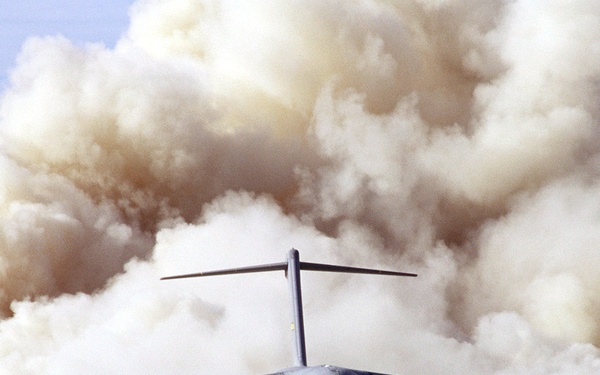 Clouds of dust billow out from behind a C-17 as it lands on the dry lake bed at Fort Irwin.