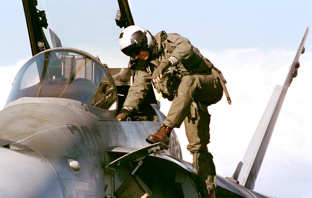An F/A-18C Hornet pilot climbs into the cockpit for flight operations off the USS Enterprise.