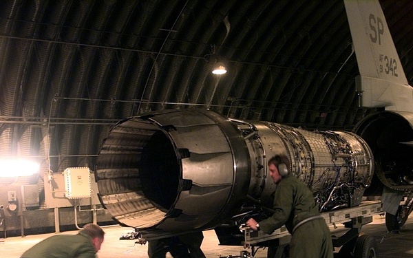 U.S. Air Force crew chiefs muscle an engine into position for installation in an F-16.
