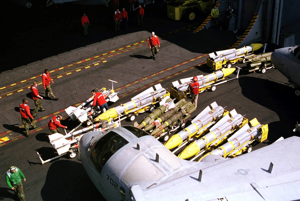 Aviation ordnancemen load missiles and bombs onto an elevator for a lift to the flight deck.