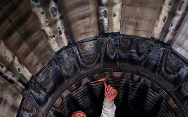 Senior Airman Matt LaNew examines the interior of the afterburner of a Fighting Falcon.