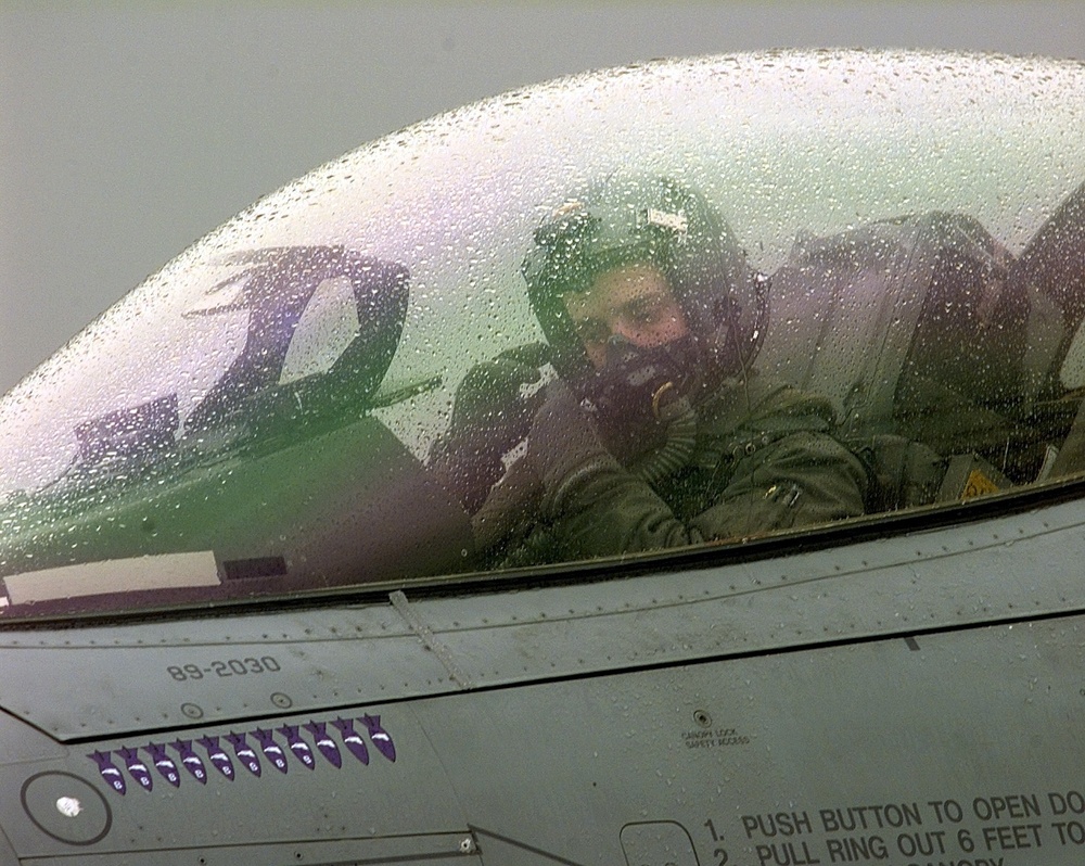 A U.S. Air Force F-16 pilot adjusts his oxygen mask as he prepares to take off from Aviano.
