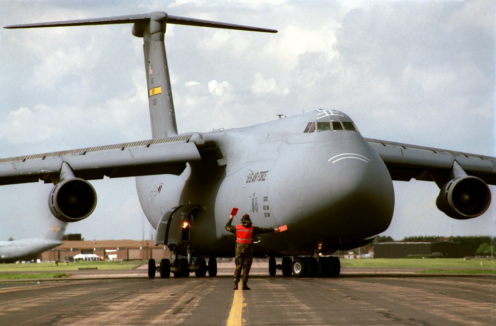 An airman directs a U.S. Air Force C-5B Galaxy to a parking position at RAF Mildenhall.
