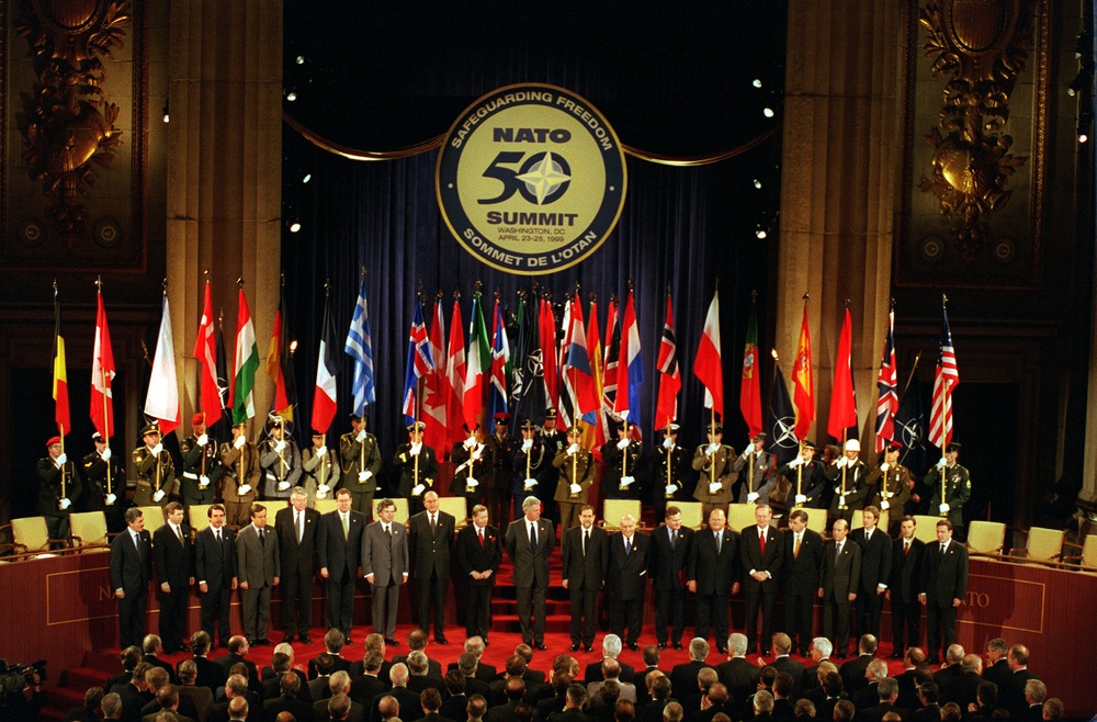 Representatives of the 19-member NATO nations stand for a group photograph.