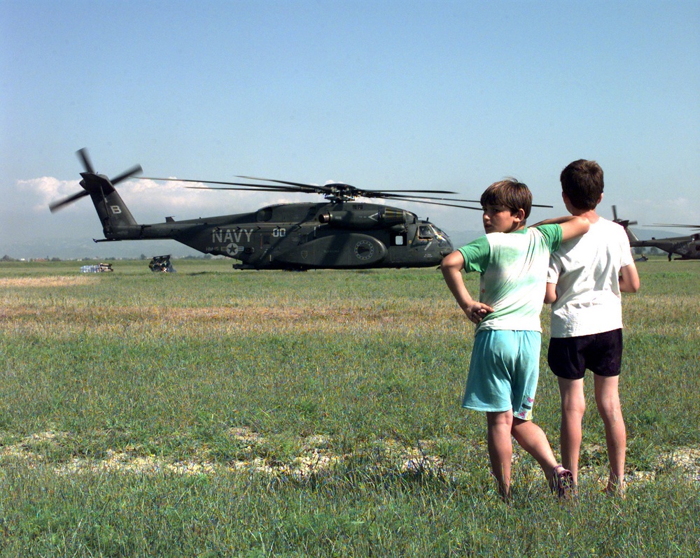 Two refugee children watch as relief supplies are unloaded from U.S. Navy MH-53E Sea Dragons.