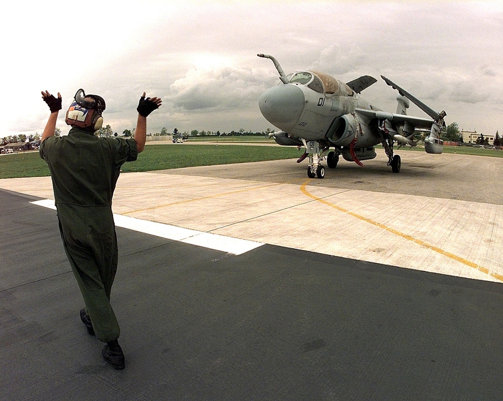 Cpl. James Bivins directs a Marine EA-6B Prowler to a spot on the ramp at Aviano Air Base.