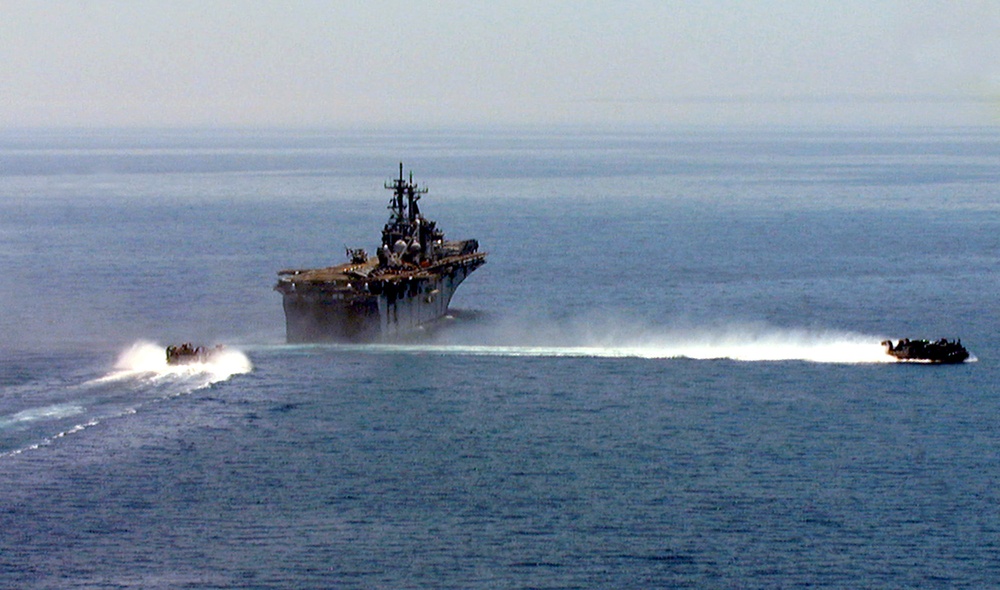 One U.S. Navy Landing Craft Air Cushioned leaves the well deck of the USS Kearsarge as another approaches.