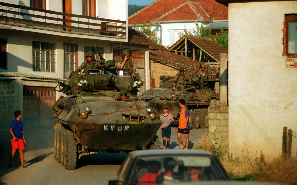 U.S. Marine Corps Light Armored Vehicles escort vehicles transporting Kosovo Liberation Army members.