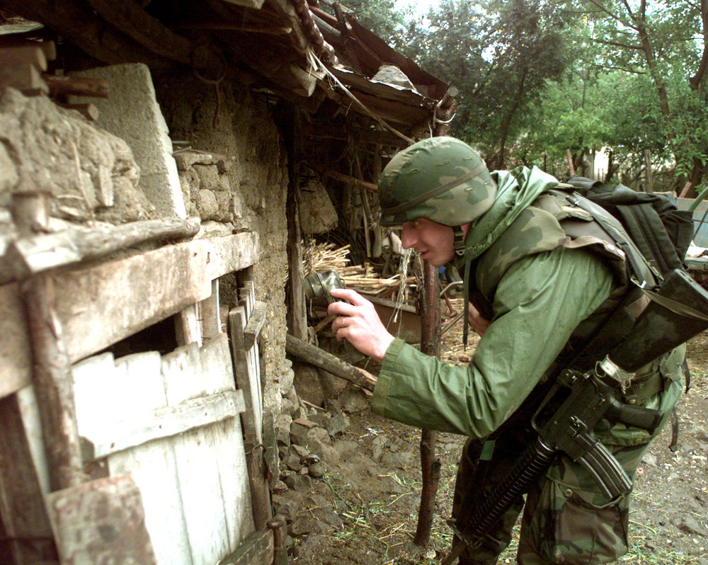 A soldier peers into a shed as he searches for automatic weapons in the town of Zitinje, Kosovo.