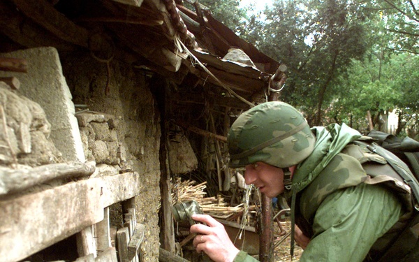 A soldier peers into a shed as he searches for automatic weapons in the town of Zitinje, Kosovo.
