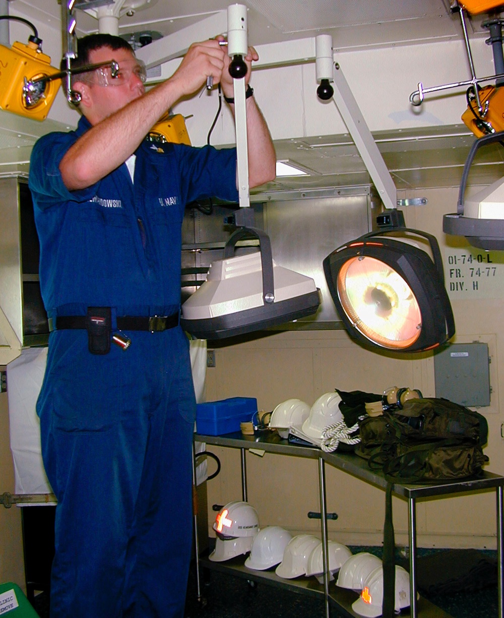 Petty Officer Lewandowski installs an examination light in a medical examining room on board the USS Kearsarge.