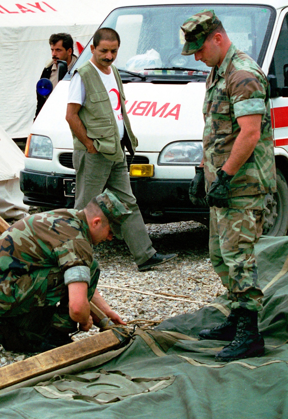 A Red Crescent Camp worker watches as U.S. Marines put up the first of several tents.