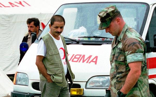 A Red Crescent Camp worker watches as U.S. Marines put up the first of several tents.