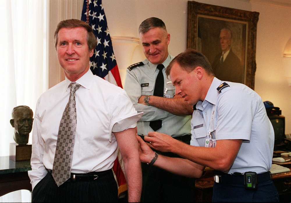 Flight Surgeon Maj. Timothy Ballard administers the final anthrax inoculation to Secretary Cohen.