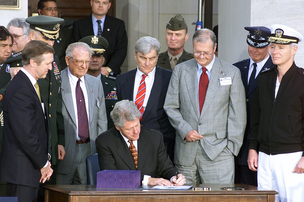 Defense officials and members of Congress surround President Clinton as he signs the National Defense Authorization Act FY 2000.